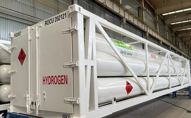 Ein weißer Container mit der Aufschrift "HYDROGEN" und einem Warnschild, der zylindrische Tanks enthält, in einer Lagerhalle.