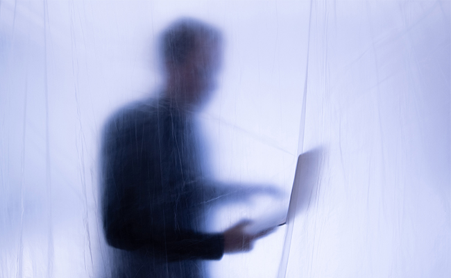 Eine verschwommene Figur einer Person, die einen Laptop hält, umgeben von einem durchscheinenden Material, das eine ätherische und geheimnisvolle Atmosphäre schafft.